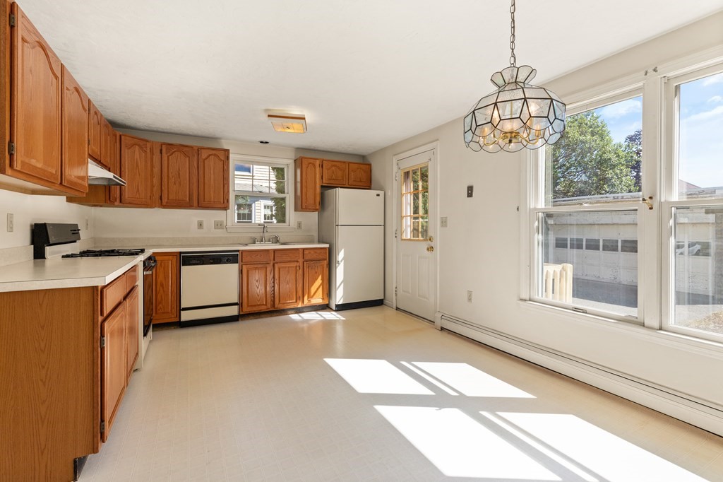Bright kitchen with wood cabinets, white countertops, and large sunlit windows.