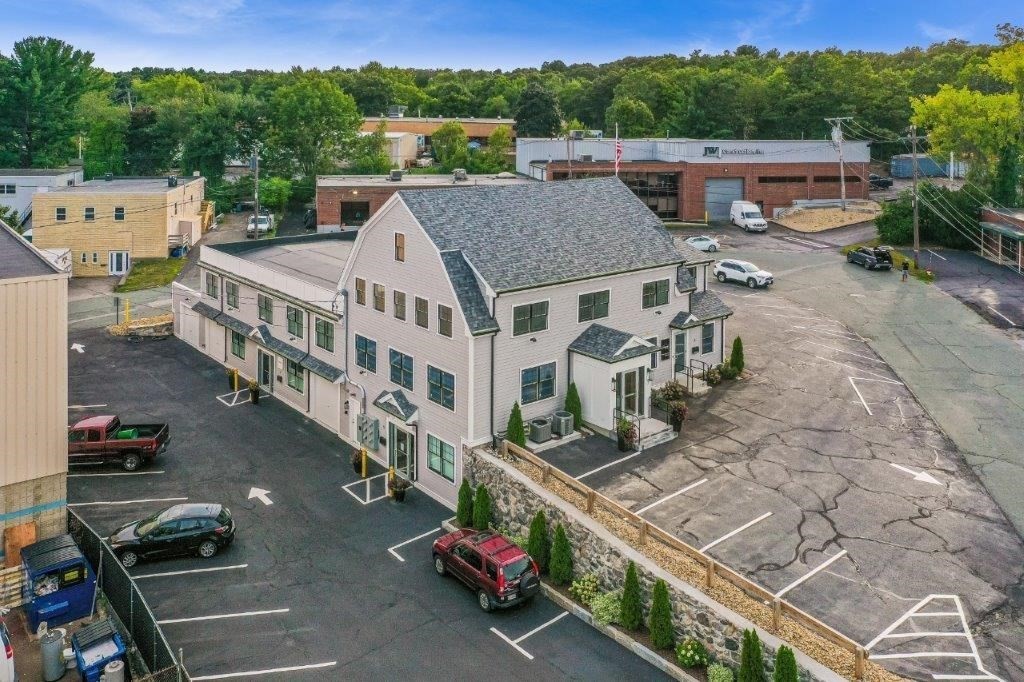 Aerial view of a two-story commercial building with a gray roof and surrounding parking lots.