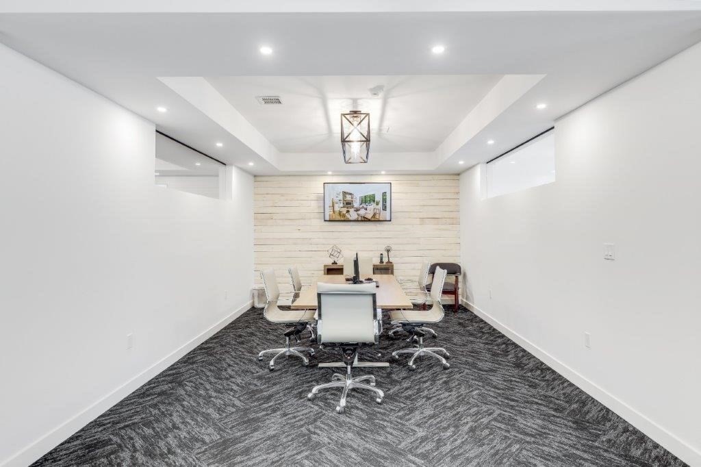 Conference room with a long table, white office chairs, and a light wood accent wall.