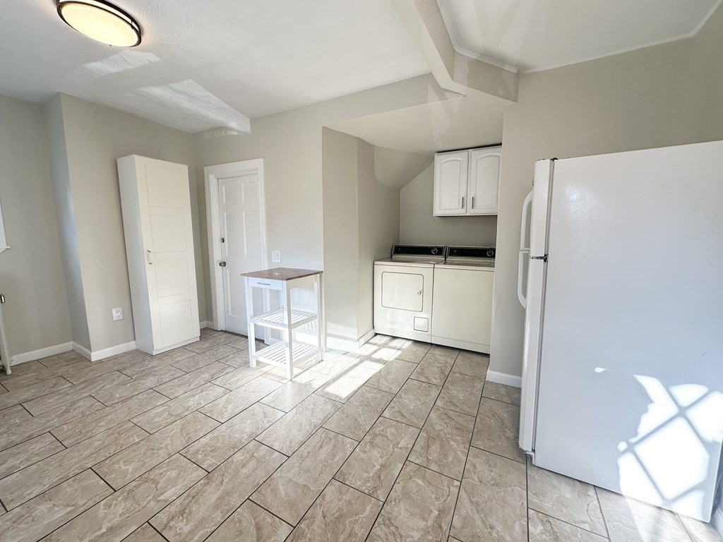 Laundry area with washer and dryer, wall cabinets, and a white refrigerator.