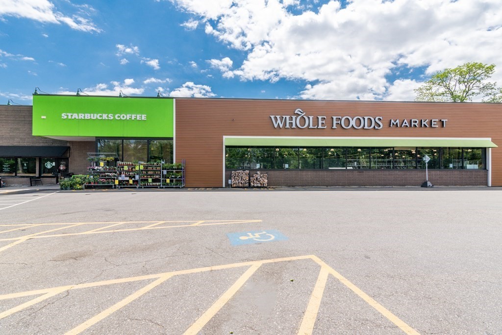 Whole Foods Market and Starbucks storefronts beside a large parking lot.