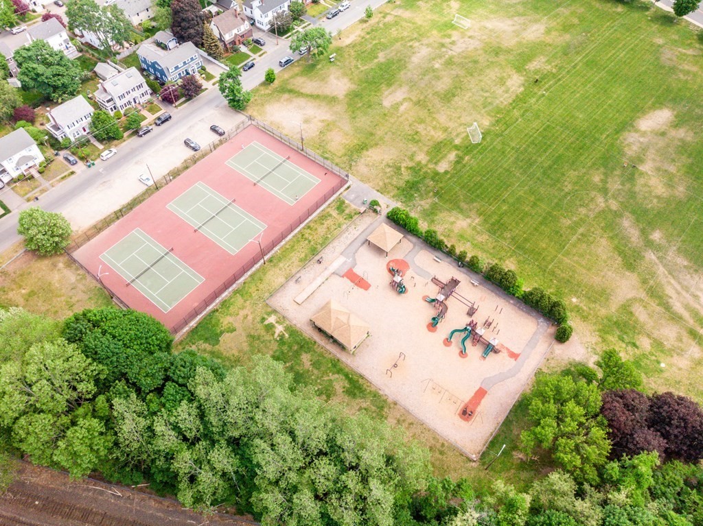 Aerial view of a park with tennis courts, a playground, and a grassy field.