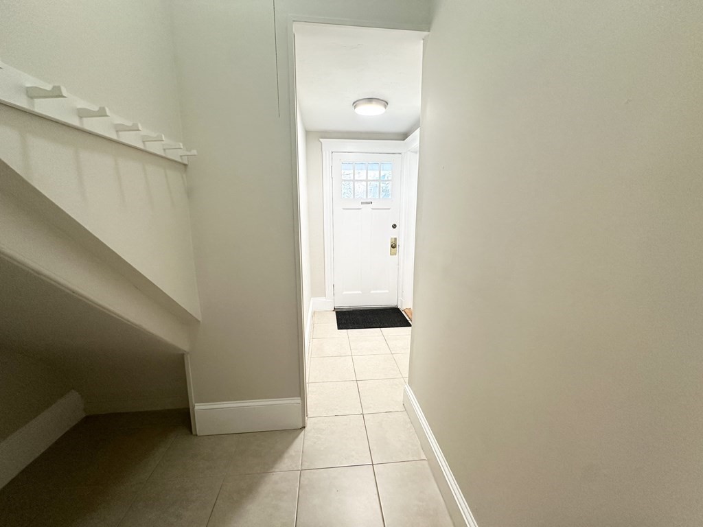 Entry hallway with tiled floor, staircase, and a white front door with window panes.