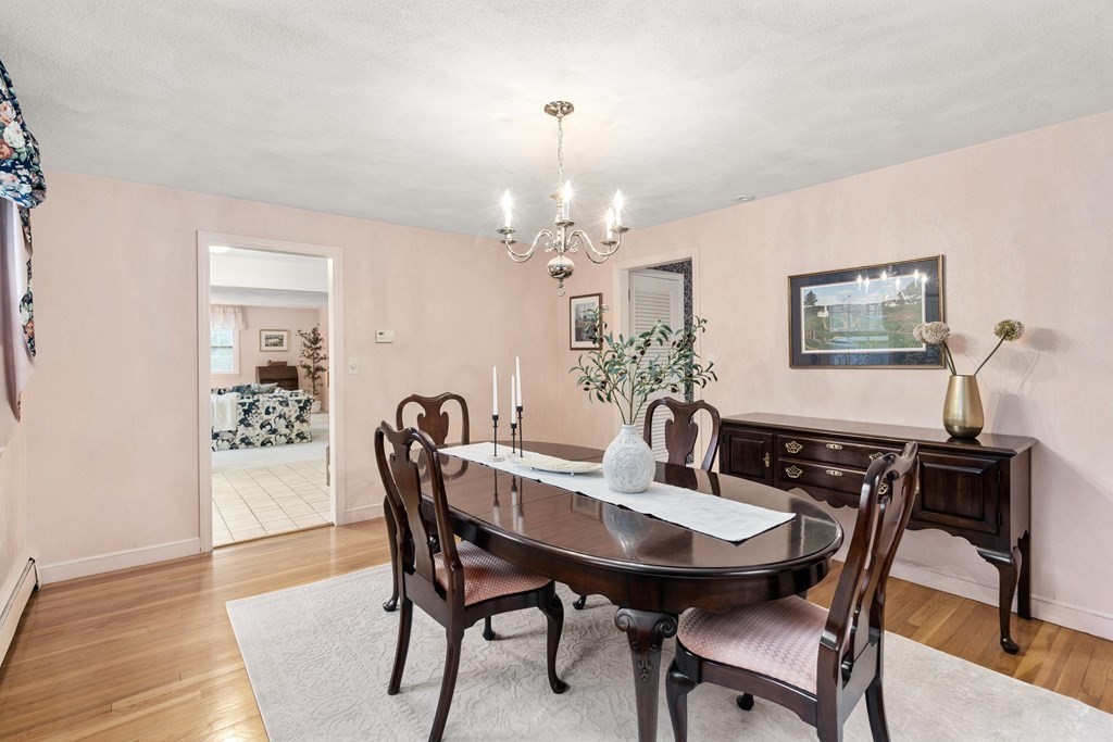 Dining room with pink walls, a dark oval table, chandelier, and hardwood floors.