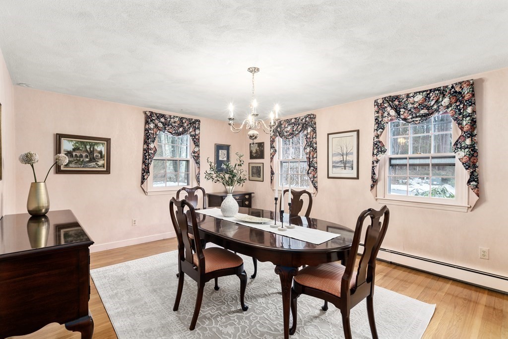 Dining room with a dark wood table, floral curtains, and snow visible through the windows.