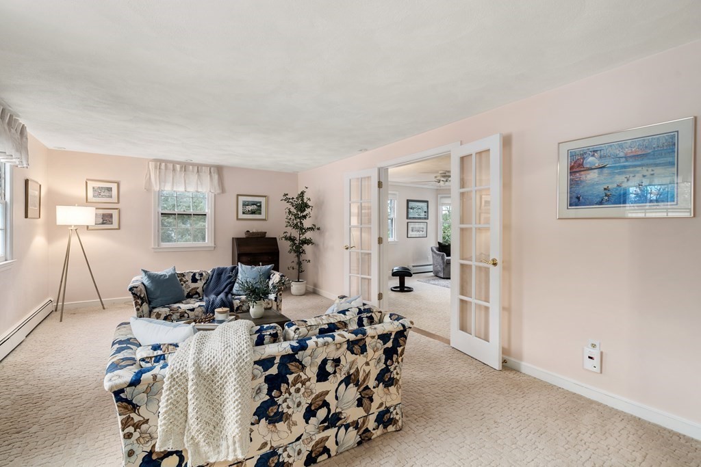 Living room with floral sofas and French doors opening to an adjoining room.