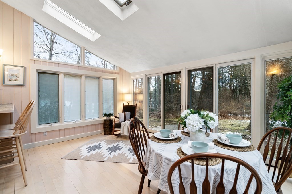 Sunroom dining area with skylights, a set table, and large windows overlooking woods.