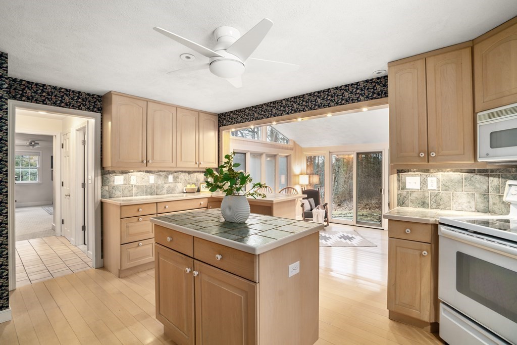 Kitchen with light wood cabinets, tiled island, and glass doors opening to a sunroom.