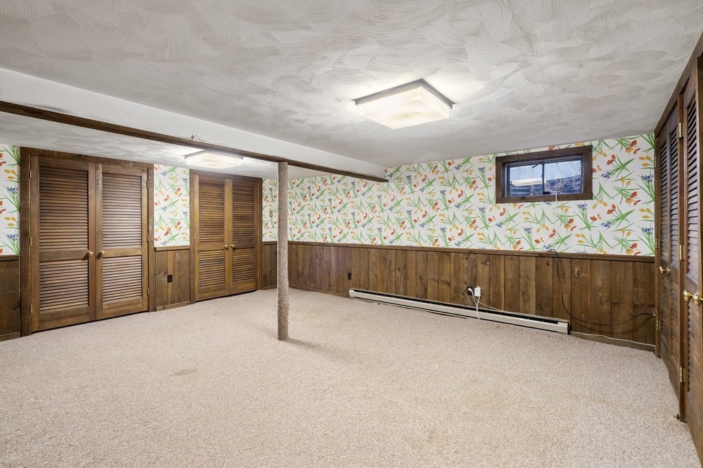 Basement room with botanical wallpaper, louvered closets, and a central support post.