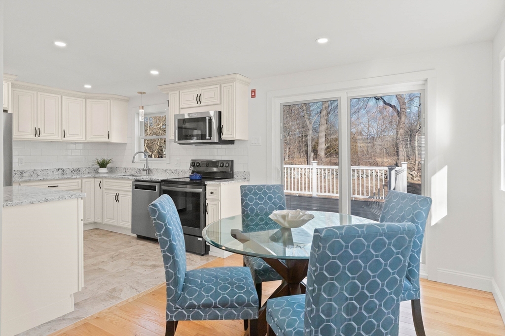 Kitchen and dining area with white cabinets, blue chairs, and sliding doors to a wooded deck.