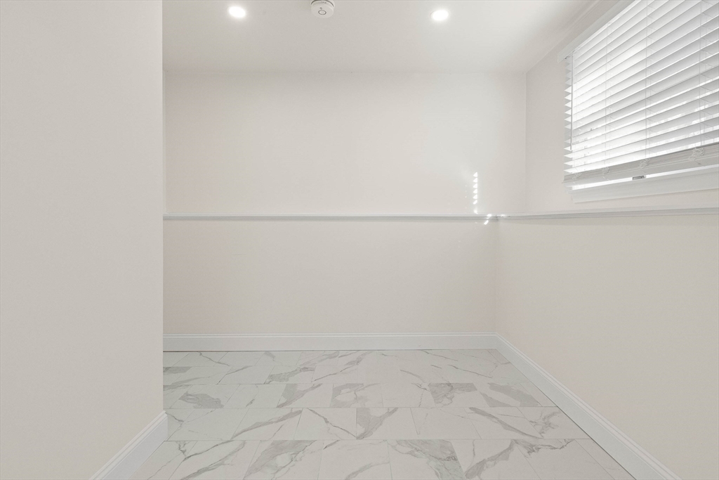 Empty room with marble-look tile flooring and a window with white blinds.