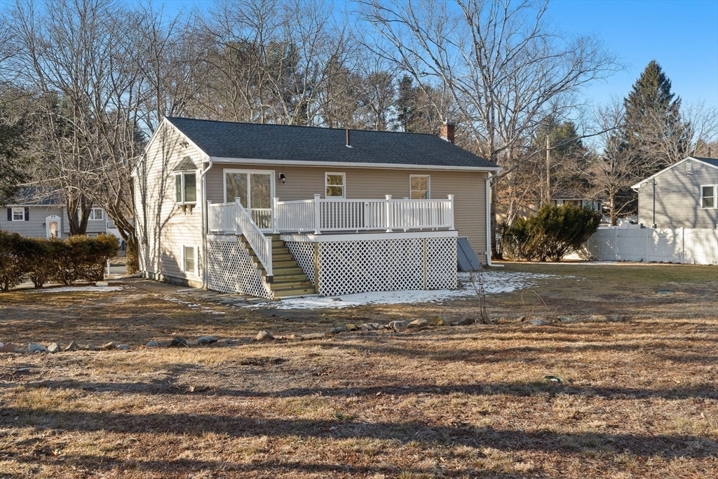 Rear of a beige house with a raised white deck and lattice skirting, beside a leafless yard with patches of snow.