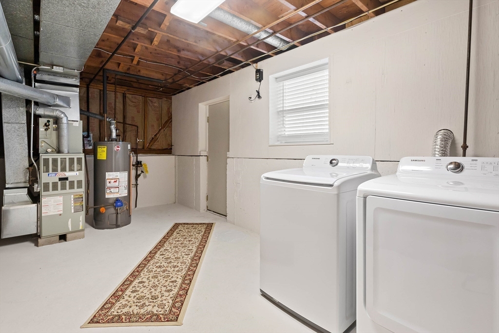 Basement laundry area with washer and dryer beside the furnace and water heater.