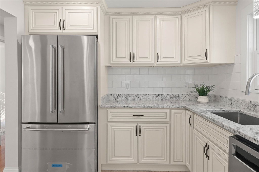 Kitchen with white cabinets, granite counters, stainless steel appliances, and a sink beneath the window.