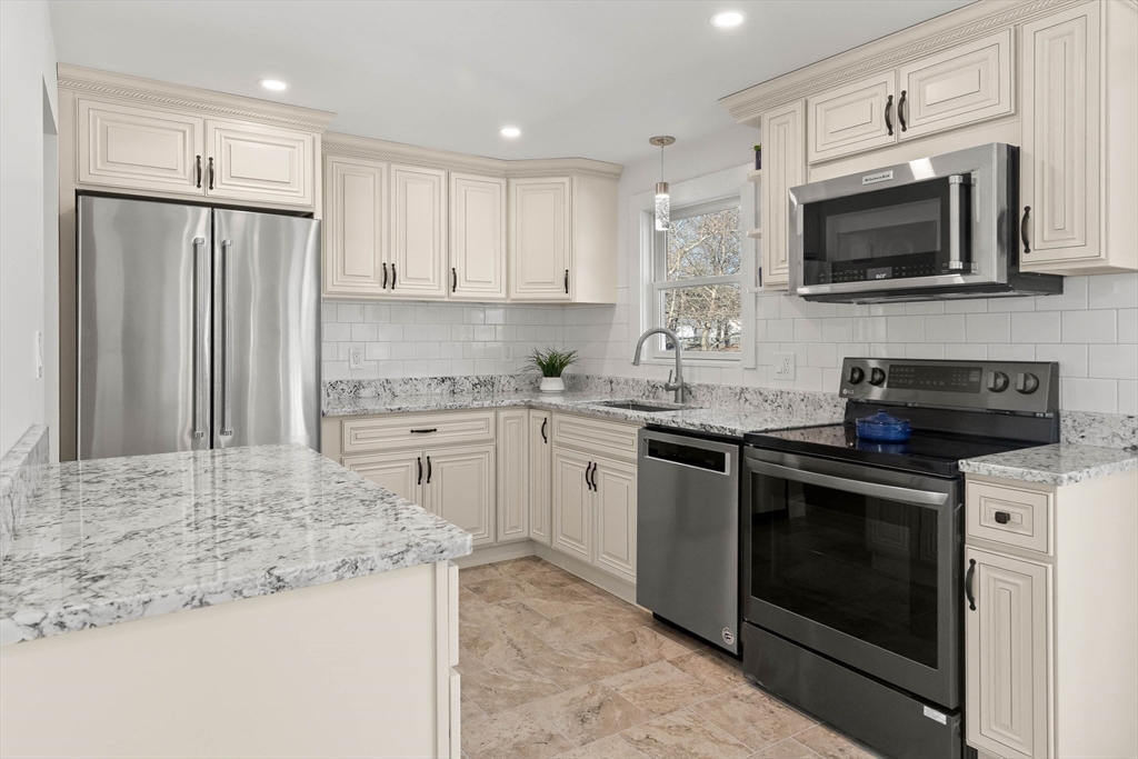 Kitchen with white cabinets, granite island, and stainless steel appliances.