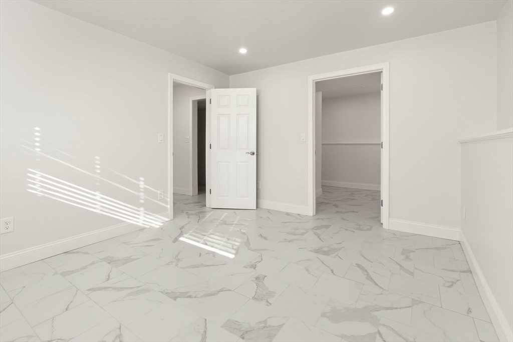 Empty room with large marble-look tile flooring and two open doorways.
