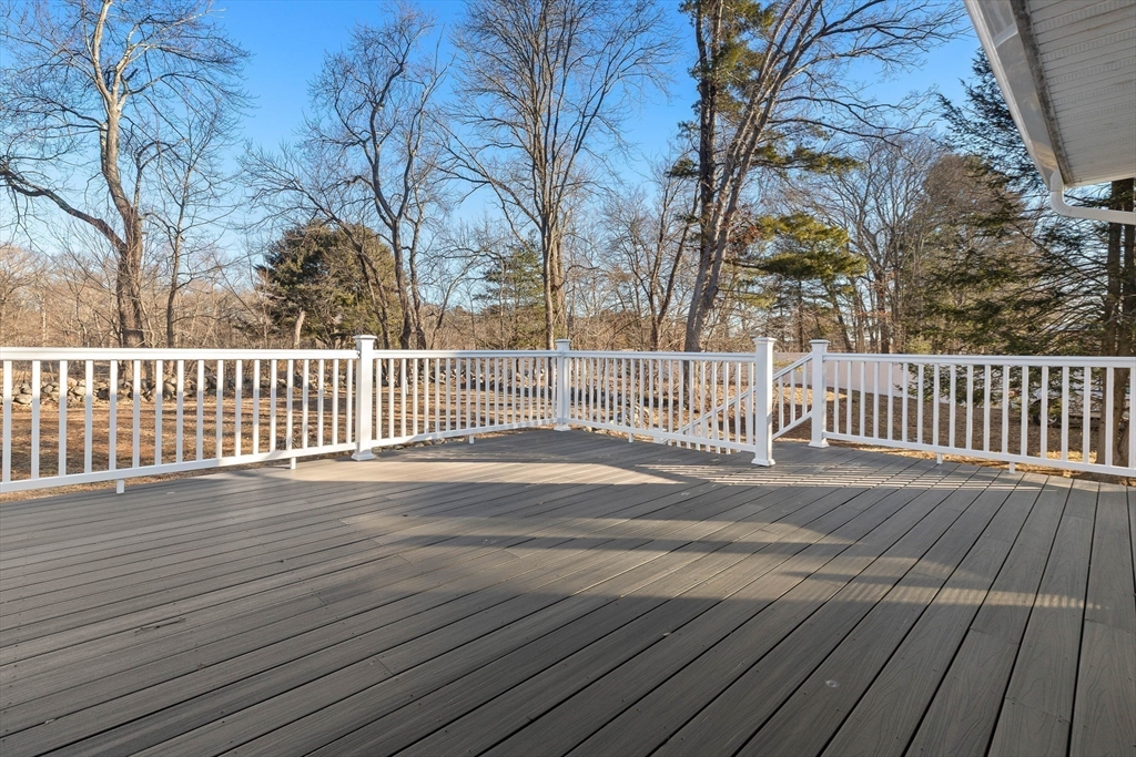 Wide composite deck with white railings overlooking a leafless wooded backyard.