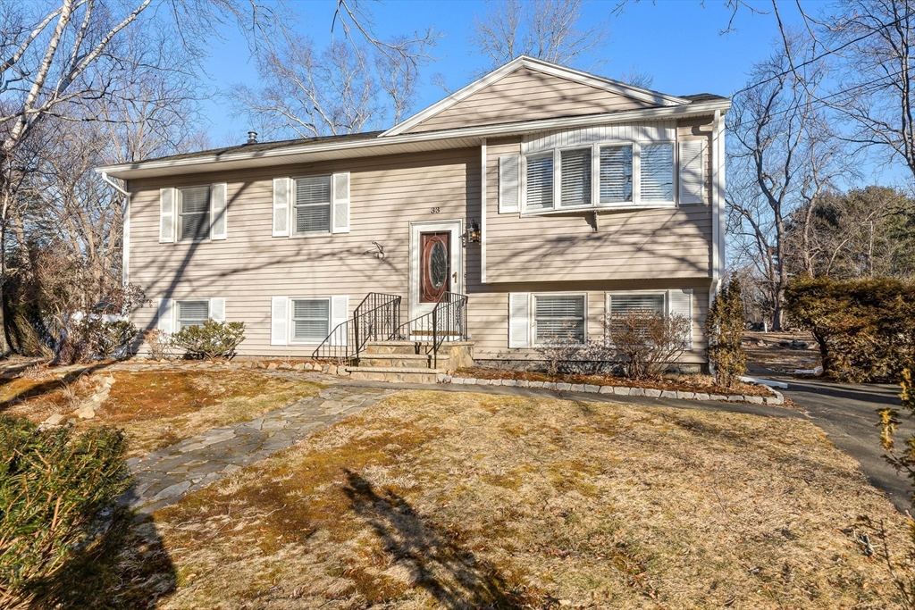 Beige split-level home with a stone walkway leading to its red front door.