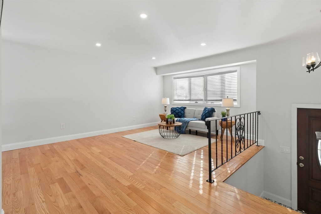 Living area with hardwood floors, a gray sofa, blue accents, and a wrought-iron railing.