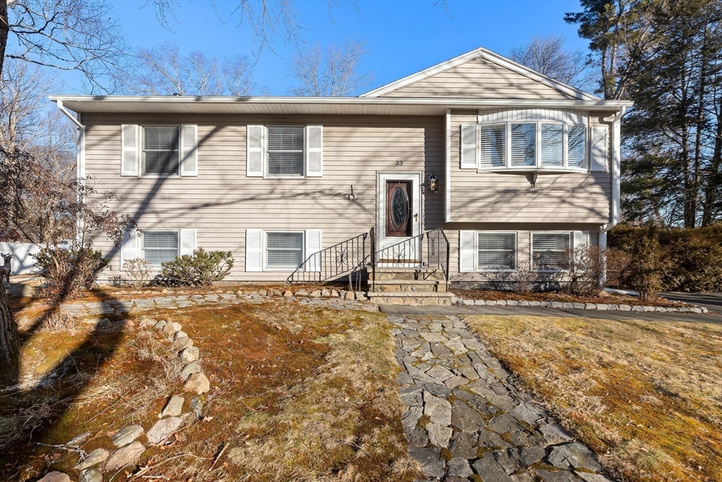 Beige split-level house with a bay window and stone walkway to the front entrance.