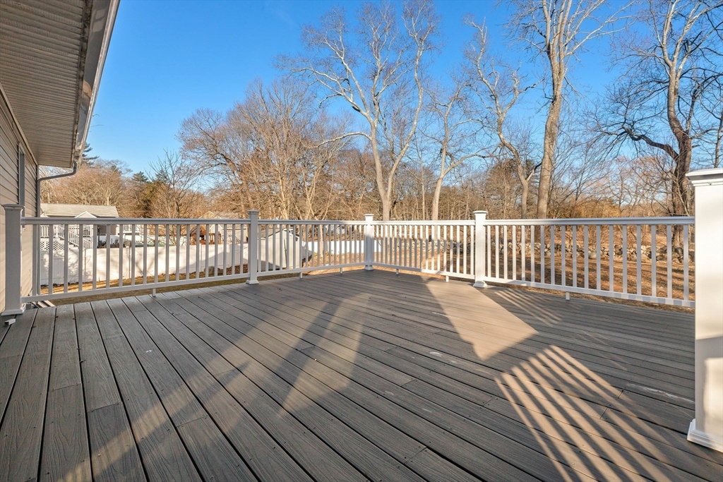 Spacious wood deck with white railings overlooking bare trees and neighboring homes.