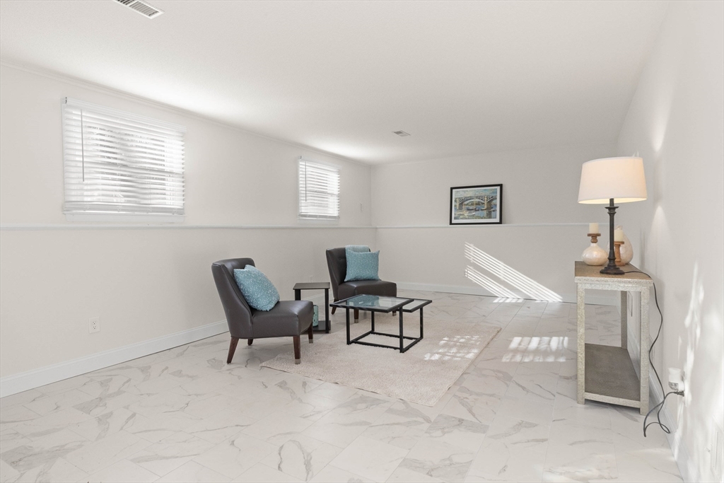 Staged living room with marble-pattern tile floors, two armchairs, and a glass coffee table.