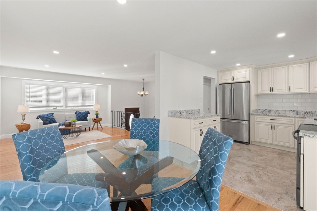 Open-plan kitchen and dining area with white cabinetry, stainless-steel appliances, and blue upholstered chairs.