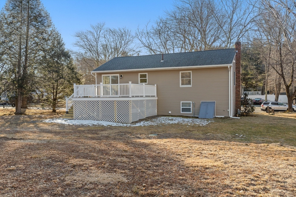 Rear of a beige home with a white-railed deck and lattice skirting.