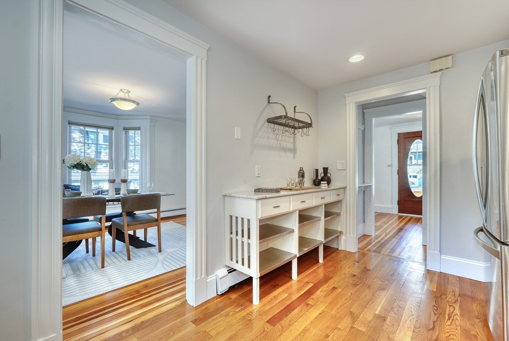 Kitchen with white built-in counter and open shelving, hardwood floors, and dining room beyond.