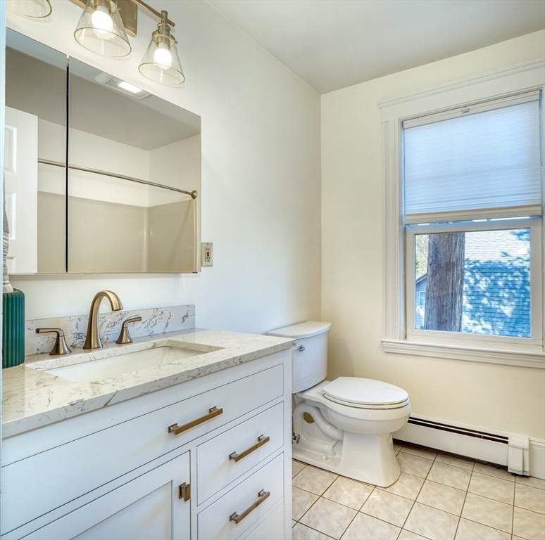 Bathroom with a white vanity, marble-look countertop, brass fixtures, and a large window.