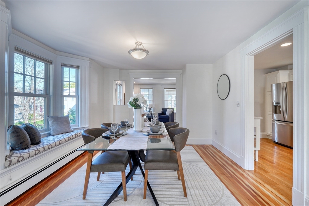 Dining room with glass-top table, window seat, and doorway to the kitchen.