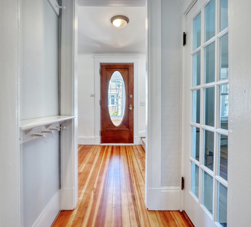 Entry hall with striped hardwood floors, a glass-inset front door, and glass-paneled doors.