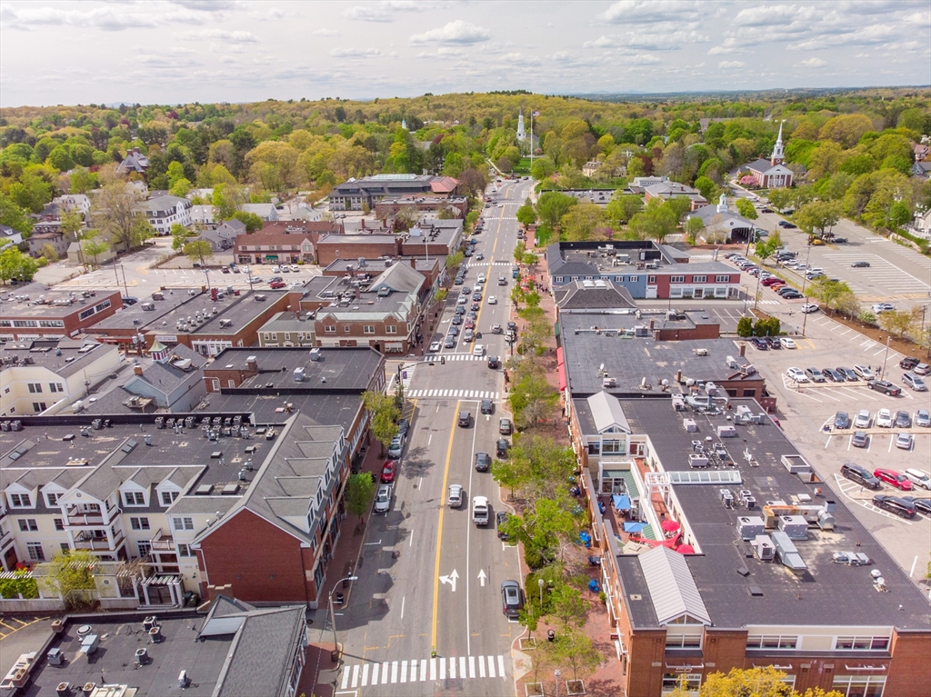 Aerial view of a town center, with Massachusetts Avenue lined by shops and parking lots.