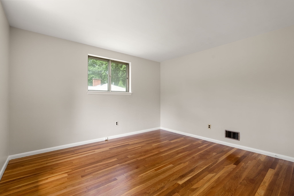Empty room with polished hardwood floors and a small window.