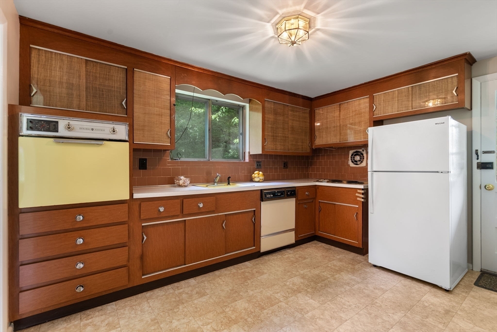 Kitchen with wood cabinetry, a yellow wall oven, and a window above the sink.
