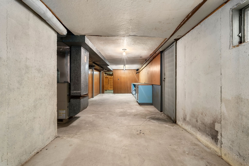 Unfinished basement with exposed utility equipment and blue cabinets along one wall.