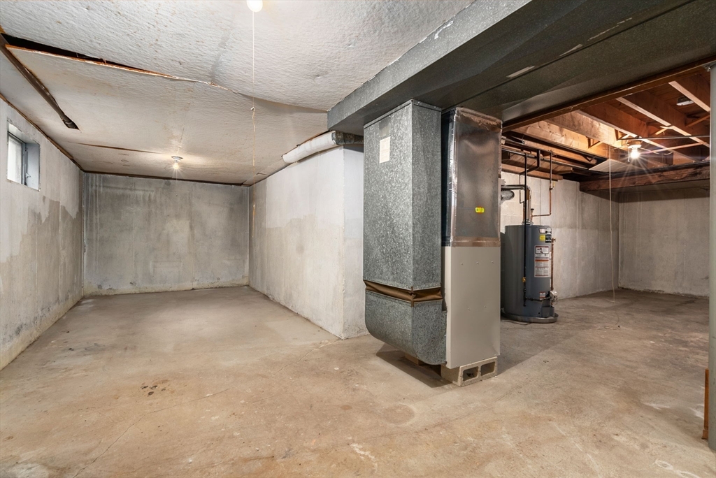 Unfinished basement with exposed HVAC ductwork and a water heater.