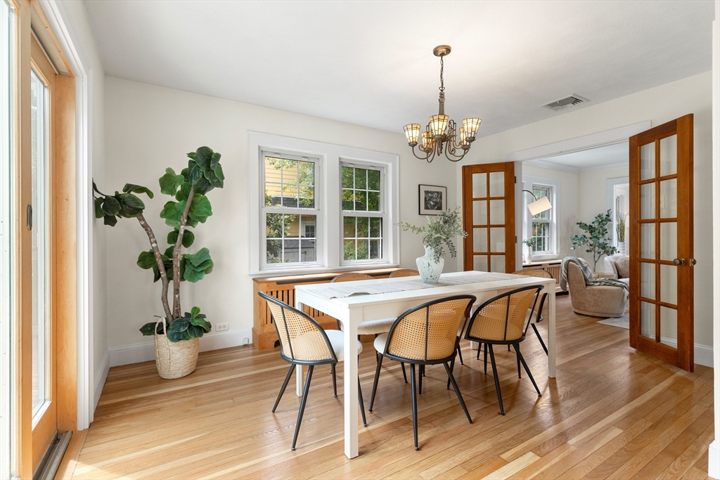 Dining room with a white table, cane chairs, hardwood floors, and open French doors to a sitting room.