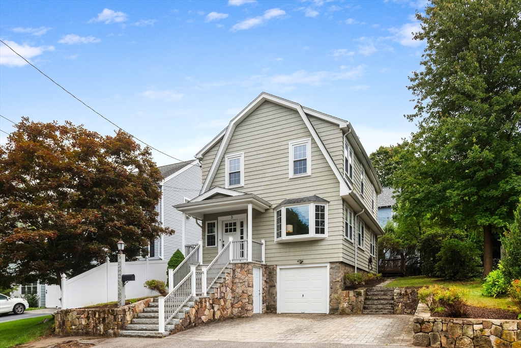Gray-green home with a stone foundation, attached garage, and paved driveway.