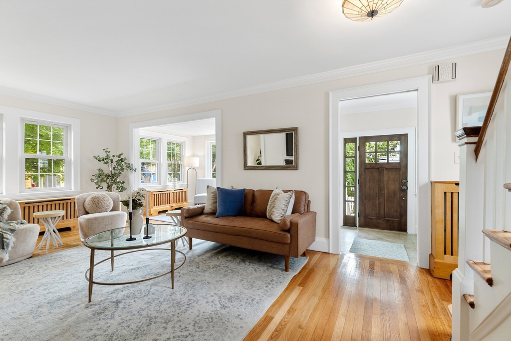Living room with a brown sofa, glass coffee table, large windows, and hardwood floors.
