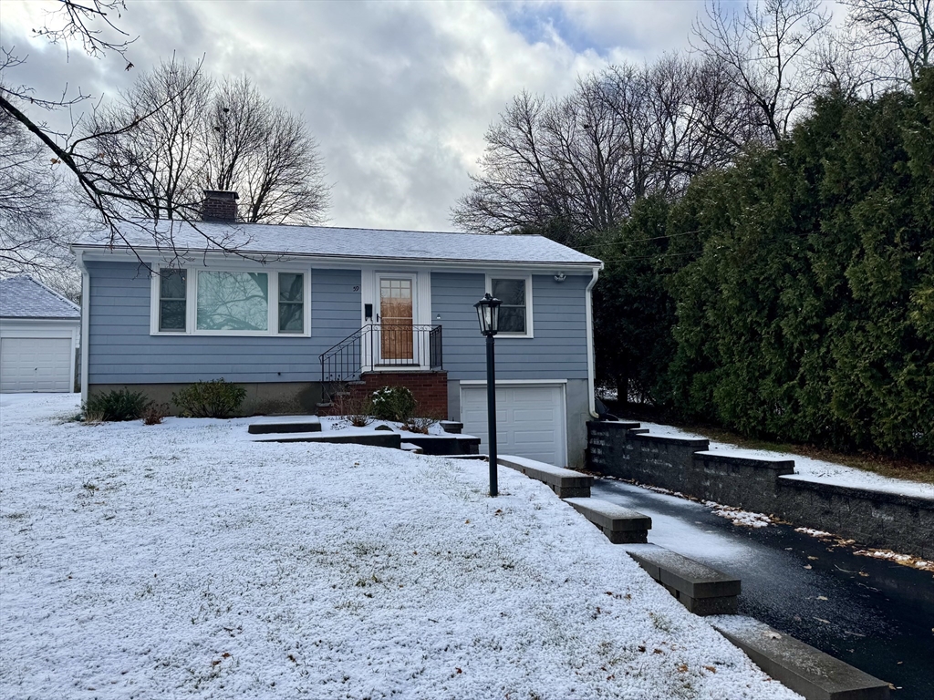 Blue-sided house with a raised entrance, garage, and snow-covered lawn.