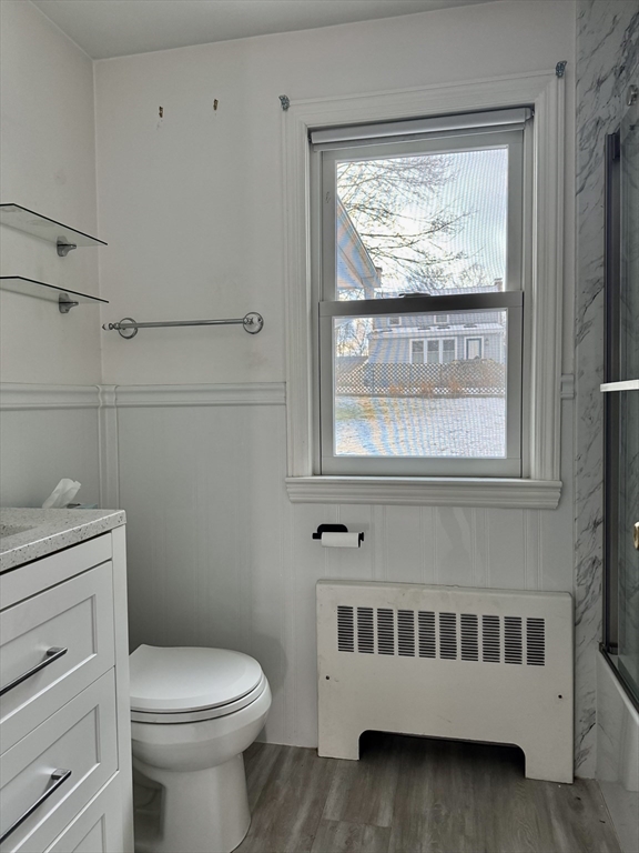Bathroom with a white vanity, marble-look shower, and window overlooking a snowy yard.