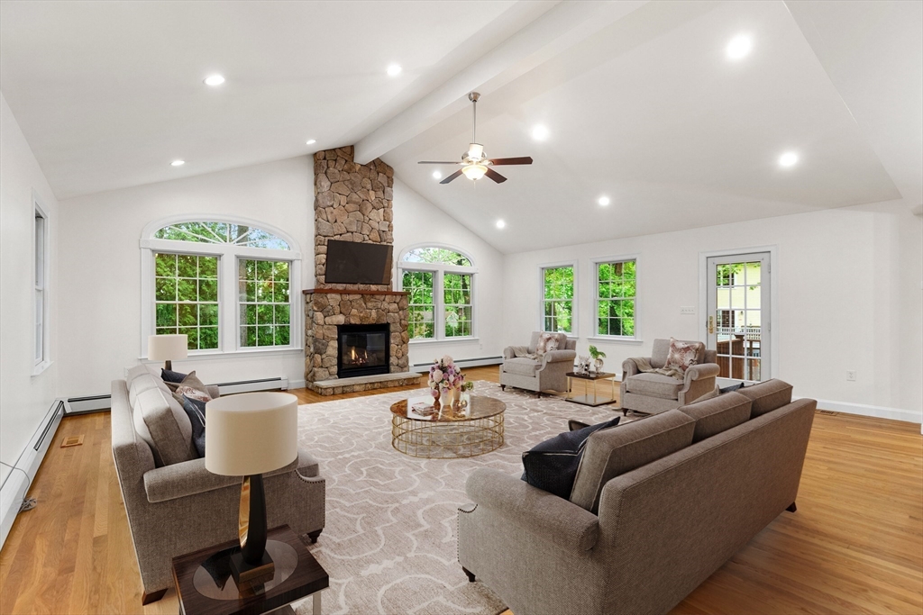 Living room with a vaulted ceiling, stone fireplace, and seating arranged around a patterned rug.