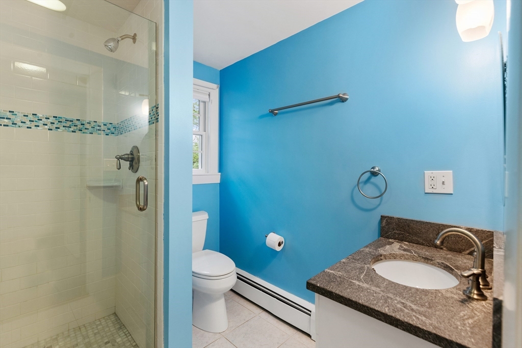 Bathroom with a glass shower, blue mosaic tile accent, and granite vanity.