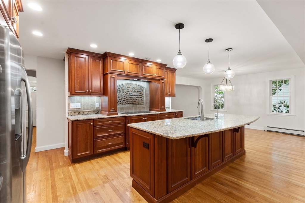 Kitchen with a large granite island, rich wood cabinetry, and hardwood floors.