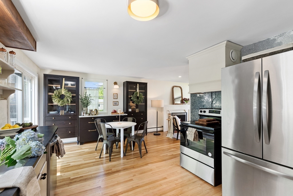 Kitchen with dark built-in cabinets, a white dining table, stainless steel appliances, and light wood floors.