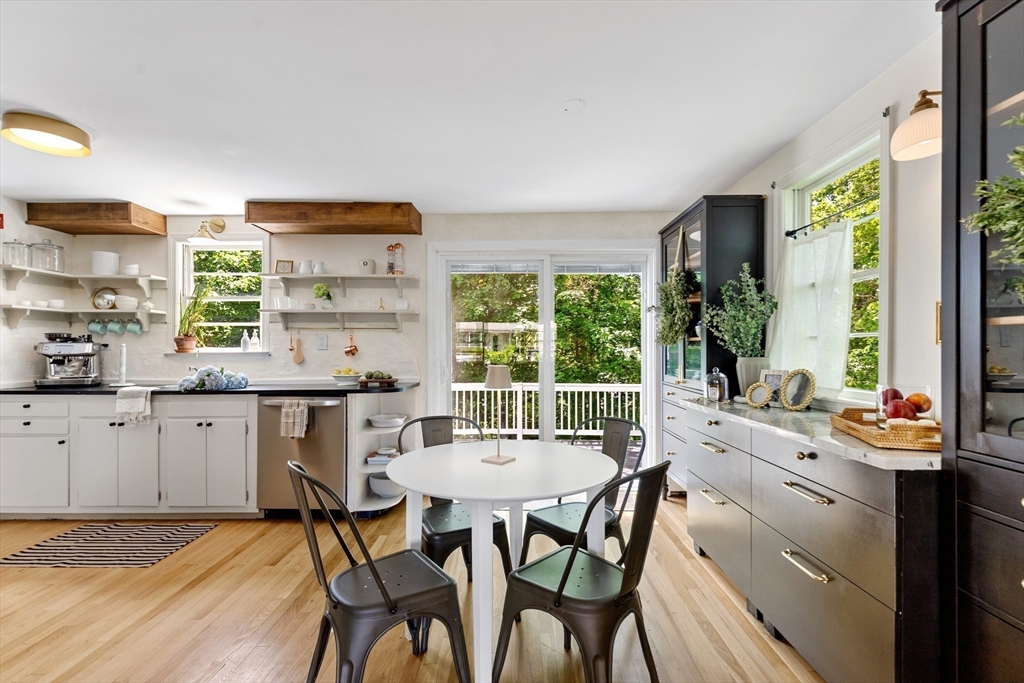 Kitchen and dining area with a round table, white cabinets, dark built-ins, and windows overlooking greenery.