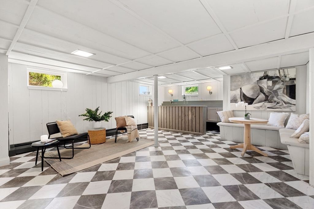 Finished basement lounge with a wood-front bar and checkerboard tile floor.