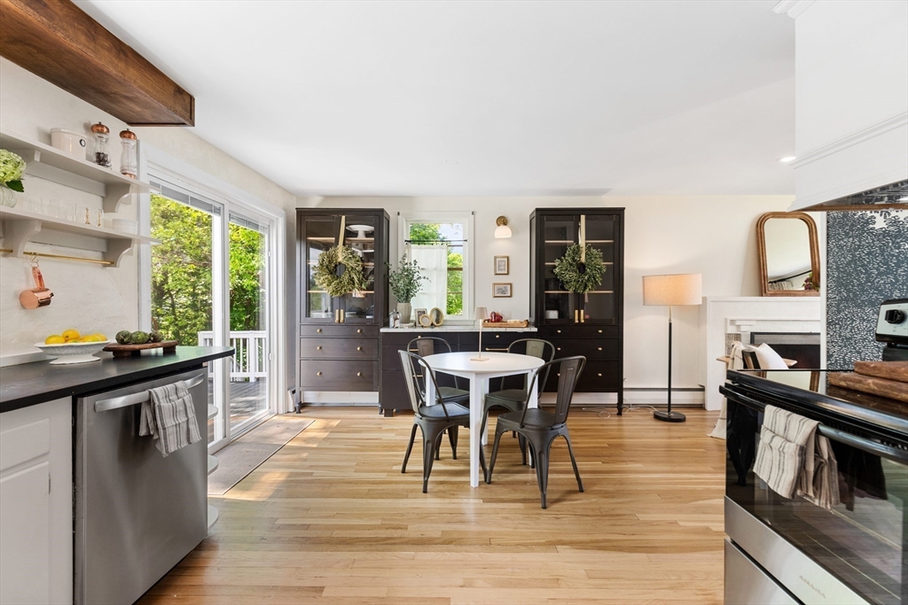 Kitchen and dining area with dark built-in cabinets, light wood floors, and glass doors to greenery.