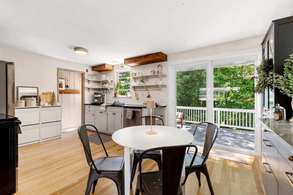 Kitchen and dining area with a round table beside sliding doors opening onto a tree-lined deck.